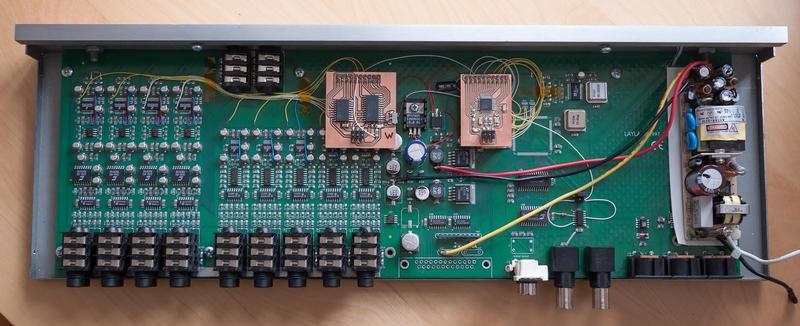 top view of the interface box with the cover removed, showing the 
        main circuit board with added wires and circuit boards with the
        microcontroller and ADAT chips
